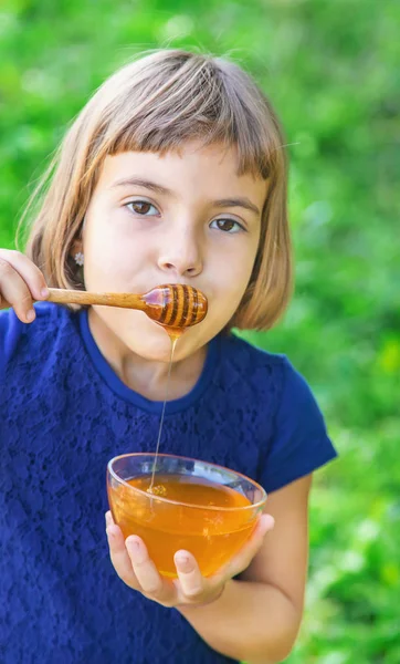 Criança um prato de mel nas mãos. Foco seletivo . — Fotografia de Stock