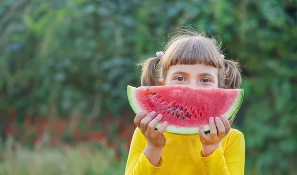 Kind eet een watermeloen in de tuin. Selectieve focus. — Stockfoto