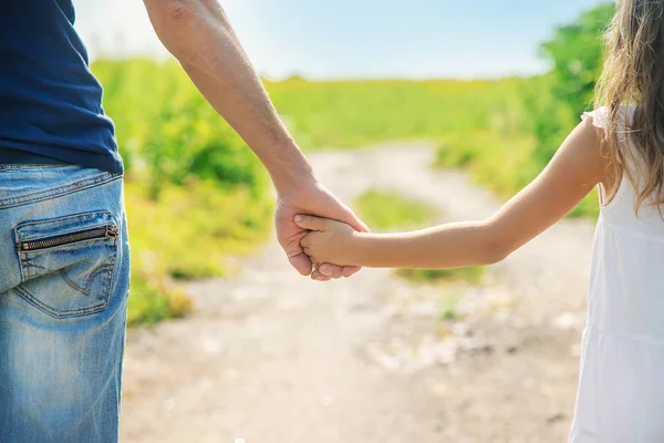 Padre e figlia camminano tenendosi per mano. Focus selettivo . — Foto Stock