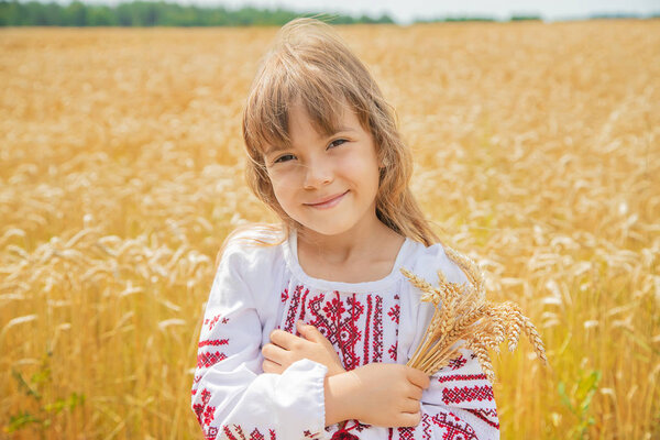 A child in a field of wheat in an embroidered shirt. Ukrainian. Selective focus.