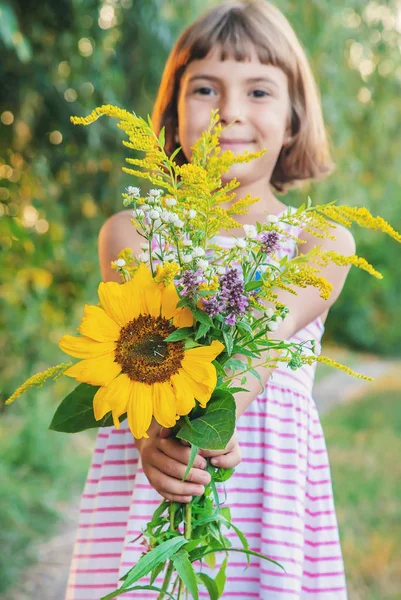 Enfant tient un bouquet de fleurs sauvages dans ses mains. Concentration sélective . — Photo