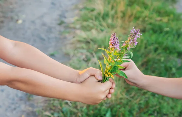 A gyermekek a virágokkal együtt tartanak kezet. Szelektív fókusz. — Stock Fotó