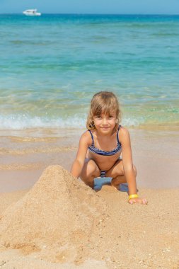 çocuk sahilde bir kumdan kale inşa eder. Seçici odaklama.
