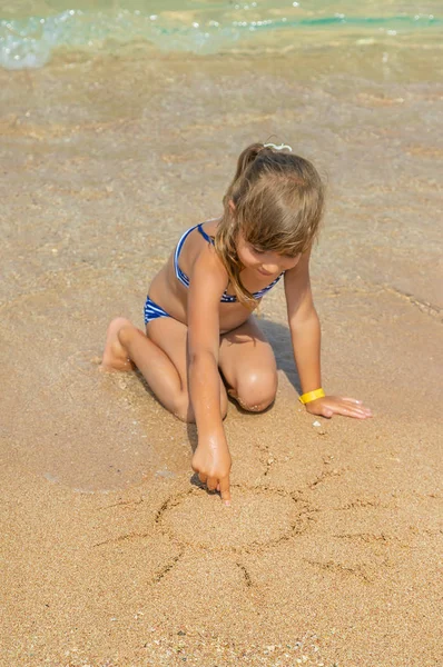 Ребенок рисует в песке на пляже. Селективный фокус . — стоковое фото