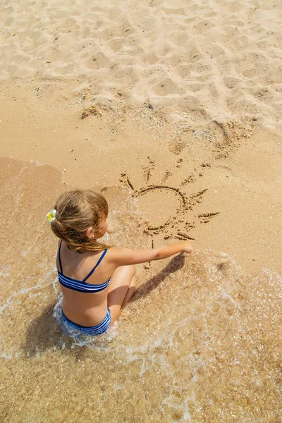 Ребенок рисует в песке на пляже. Селективный фокус . — стоковое фото