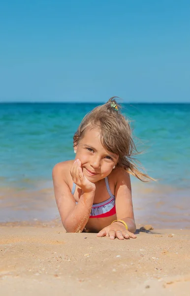 Niño se encuentra en la arena en la playa. Enfoque selectivo . —  Fotos de Stock