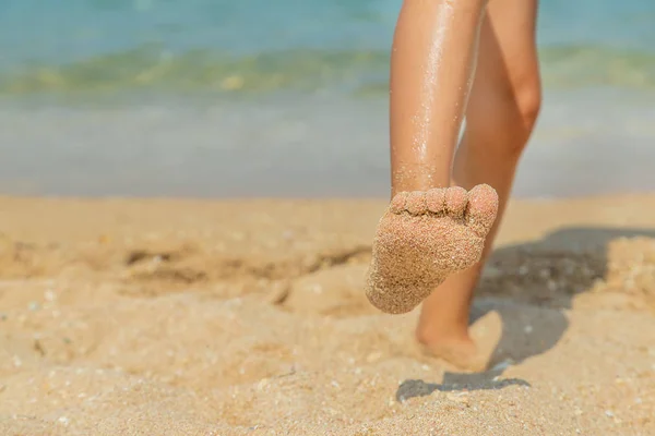 Kind spaziert am Strand entlang und hinterlässt Spuren im Sand. Selektiver Fokus. — Stockfoto