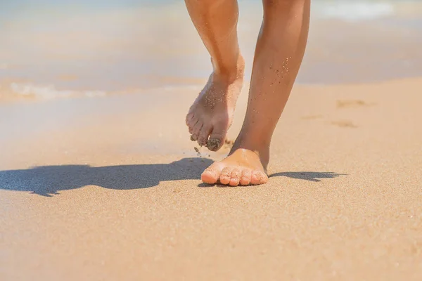 Barnpromenader längs stranden lämnar fotavtryck i sanden. Selektivt fokus. — Stockfoto