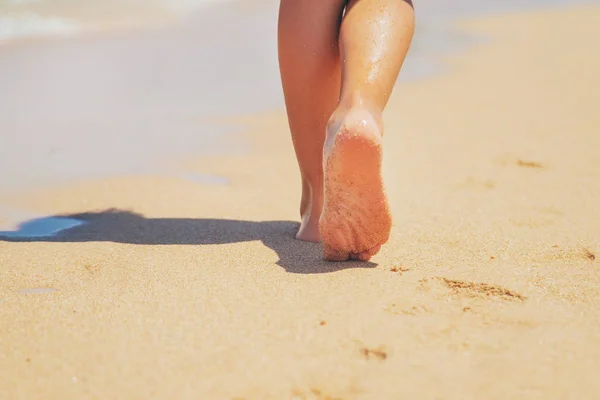 子供は砂の中に足跡を残してビーチに沿って歩きます。選択フォーカス. — ストック写真