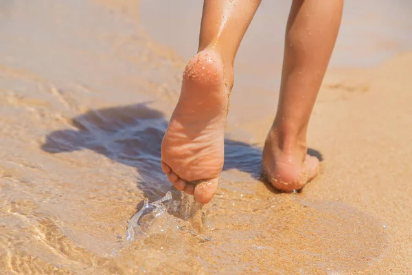 Niño camina a lo largo de la playa dejando huellas en la arena. Enfoque selectivo . — Foto de Stock