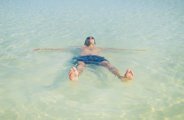 A man swims in the sea lying on his back. Selective focus. — Stock Photo, Image