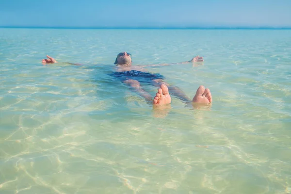 Un uomo nuota nel mare sdraiato sulla schiena. Focus selettivo . — Foto Stock