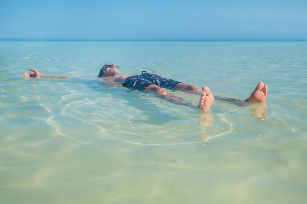 Человек плавает в море, лежа на спине. Селективный фокус . — стоковое фото