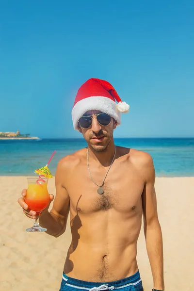 Der Mann mit dem Weihnachtsmann-Hut ruht auf dem Meer. trinkt einen Cocktail. Selektiver Fokus. — Stockfoto