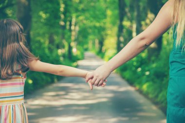 Anne ve çocuk el ele tutuşur. Seçici odaklanma. Doğa.