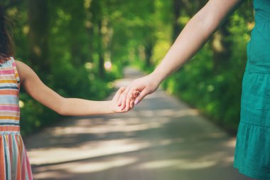 Anne ve çocuk el ele tutuşur. Seçici odaklanma. Doğa.