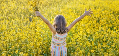 Sarı tarlada bir çocuk, hardal açar. Seçici odaklanma. Doğa.