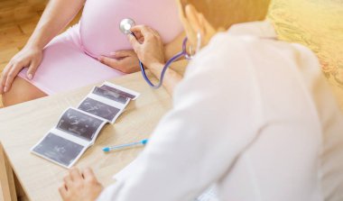 Klinikteki bir doktor hamile bir kadını muayene ediyor. Seçici odaklanma. İnsanlar.