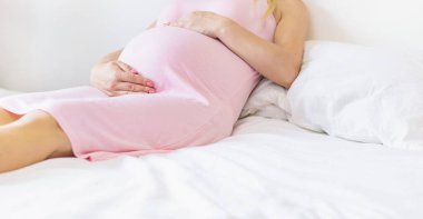 Yatakta hamile bir kadın karnına sarılıyor. Seçici odaklanma. insanlar.