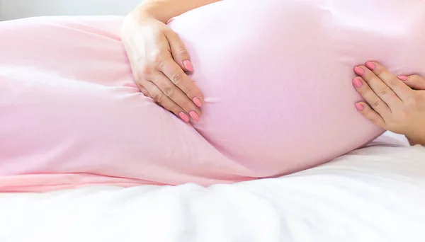 一个躺在床上的孕妇抱着她的胃 有选择的重点 — 图库照片