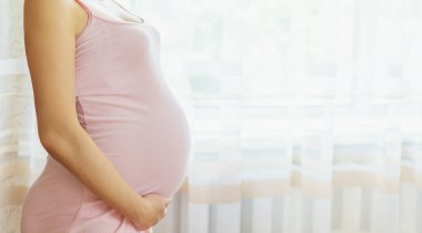 Yatakta hamile bir kadın karnına sarılıyor. Seçici odaklanma. insanlar.