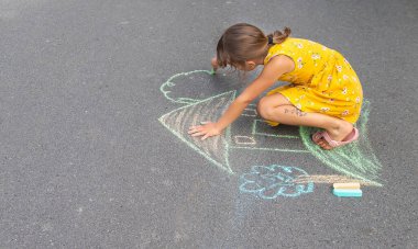 Çocuk asfalta bir ev çiziyor. Seçici odaklanma. Çocuk.