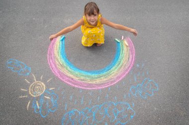 Bir çocuk asfalta bir gökkuşağı çizer. Seçici odaklanma. çocuk.