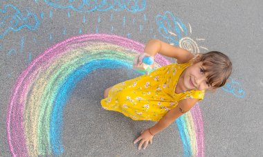 Bir çocuk asfalta bir gökkuşağı çizer. Seçici odaklanma. çocuk.