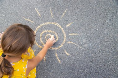 Çocuk asfalta güneşi çizer. Seçici odaklanma. Doğa.