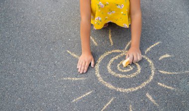 Çocuk asfalta güneşi çizer. Seçici odaklanma. Doğa.