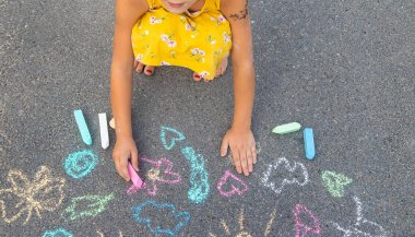 Çocuk asfalta tebeşirle çizer. Seçici odaklanma. Çocuk.