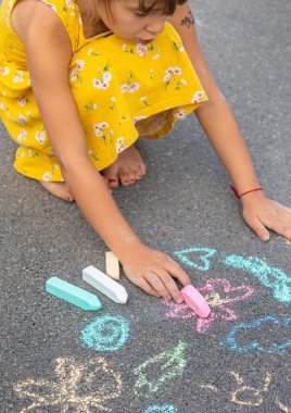 Çocuk asfalta tebeşirle çizer. Seçici odaklanma. Çocuk.