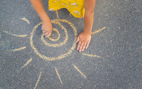 子供はアスファルトの上に太陽を描きます 選択的フォーカス — ストック写真