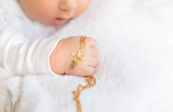 The sacrament of the baptism of a child. The kid is holding a cross. Selective focus. People.