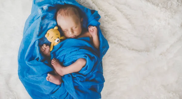 A newborn baby sleeps with a teddy bear. Selective focus. people.