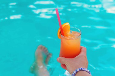 Yüzme havuzunun arka planında bir kadının elinde kokteyl. Seçici odaklanma. deniz.