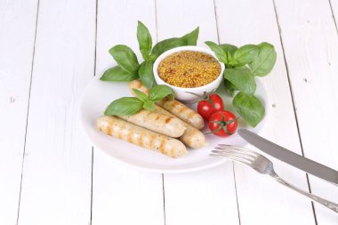 Domates, fesleğen ve hardal ile bir ızgarada pişmiş sosis