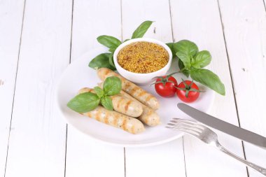 Domates, fesleğen ve hardal ile bir ızgarada pişmiş sosis