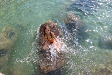 Kız denizde banyoları. Deniz suyu taş kız