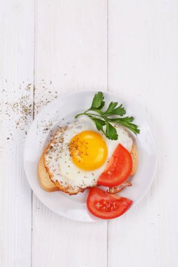 Bir dilim domates ve maydanoz ile beyaz ekmek üzerinde kızarmış yumurta