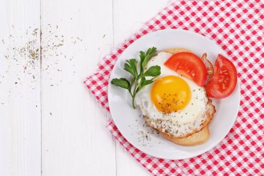 Bir dilim domates ve maydanoz ile beyaz ekmek üzerinde kızarmış yumurta