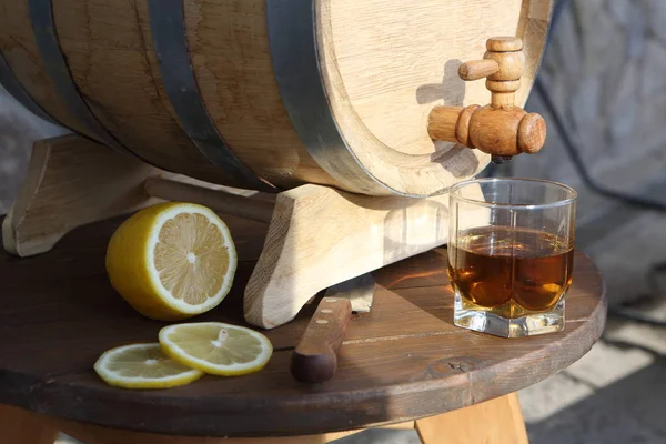 Brandy with lemon near oak barrel on a wooden tableBrandy with lemon near oak barrel on a wooden table