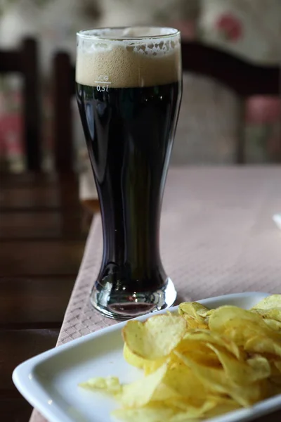 Chips with dark beer. Dark beer in a tall glass