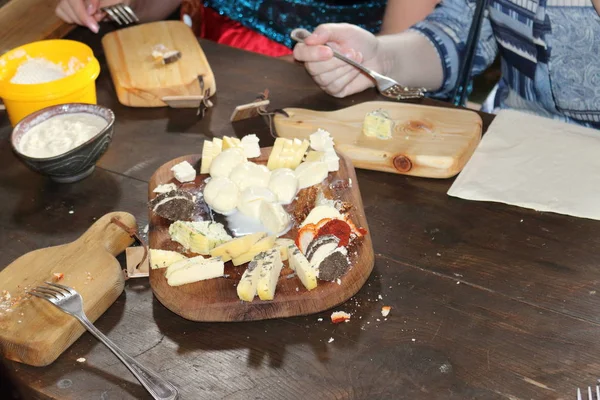 Cheese platter. Slicing cheeses on a wooden plate.