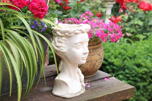 Plaster statue on a wooden table near the flowers