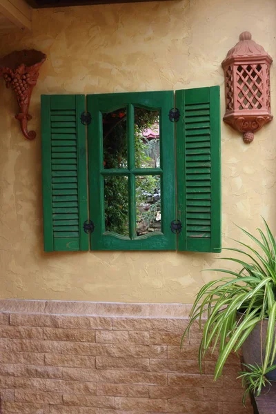 Decorative window with green wooden shutters on the wall of a country house