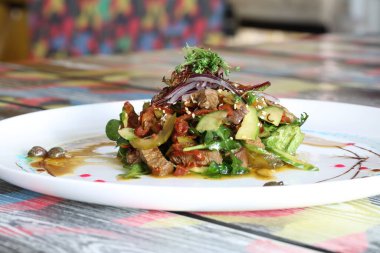 Güveçte et, sebze, roka ve avokado.