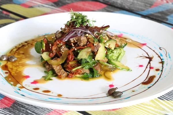 stewed meat with vegetables with arugula and avocado