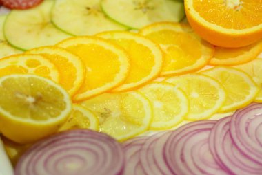 Portakal, limon, elma ve soğan dilimleri halka şeklinde dilimlenmiş.