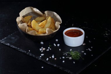 Siyah arka planda kırsal patatesler. Soslu köy usulü patates.